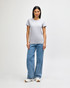 A grey midweight t-shirt on a model, paired with blue jeans and white shoes. The t-shirt has a logo.