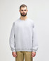 A grey Gildan Softstyle adult sweatshirt worn by a model, featuring a round neckline and long sleeves.