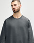 An olive green Gildan Softstyle adult sweatshirt displayed on a male model, featuring a simple design and crew neck.