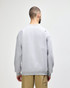 A grey Gildan Softstyle adult sweatshirt viewed from the back, worn with dark jeans. It features a logo.