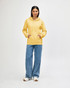 A yellow hooded sweatshirt worn by a model, paired with black jeans and sneakers, featuring a logo.