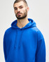 A blue Gildan Softstyle adult hooded sweatshirt worn by a model adjusting the hood. The sweatshirt has a logo.