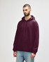 A burgundy adult hooded sweatshirt, featuring a front pocket and a drawstring hood. The model stands casually.