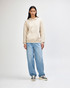 A unisex hooded sweatshirt in beige featuring a front pocket and a soft fleece material, worn with light blue jeans.