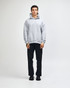 A unisex grey hooded sweatshirt with a kangaroo pocket, paired with light blue jeans and black sneakers.