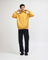 A unisex hooded sweatshirt in mustard yellow with a front pocket and a relaxed fit, featuring a logo.