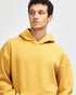 A unisex hooded sweatshirt in a warm gold colour, featuring a front pocket and a relaxed fit. It has a logo.