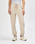 Unisex sweatpants in beige with an elastic waistband and cuffed ankles, paired with a light pink sweat top.