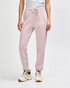 Unisex sweatpants in soft pink, featuring an elastic waistband and cuffs, shown with a pair of sneakers.