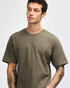 A model wearing an olive green unisex short sleeve t-shirt, featuring a logo on the shirt.