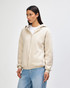 A unisex full zip hooded sweatshirt in a light beige colour, featuring a hood and a zip closure, shown on a model.