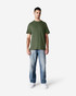 A man wearing a green Gildan Light Cotton T-Shirt paired with light blue jeans, standing against a plain background.