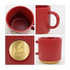 A red ceramic coffee mug with a ribbed design and a metallic bronze base, featuring a logo on one side.