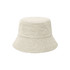 A dual-material reversible bucket hat in a light beige colour with a textured finish. It features a logo.