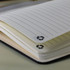 An A5 notebook with lined pages, featuring a black cover and a recycling symbol on the tabs.
