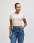 A fitted women's crop t-shirt in beige, paired with high-waisted blue jeans. The shirt has a logo.