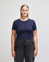 A navy blue crop fitted t-shirt on a model, paired with black high-waisted jeans. The shirt has a logo.