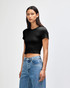 A fitted black women's crop t-shirt with short sleeves. The model is wearing it with high-waisted jeans.