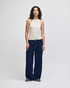 A fitted tank in beige worn with wide-leg denim jeans, featuring a model against a plain background.