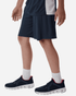 A close-up of a person wearing navy shorts and athletic shoes, with a white and navy shirt. The outfit includes a logo.