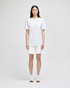 White cotton gym shorts displayed on a model, featuring a logo, paired with a matching white top and white sneakers.