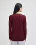 A long-sleeve t-shirt in burgundy, featuring a simple design and a logo on the back.