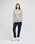 A long-sleeve t-shirt in a light grey colour, worn with navy pants, featuring a logo on the shirt.