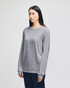 A grey Champion adult long-sleeve t-shirt displayed on a model, featuring a logo on the sleeve.