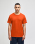 An orange Champion adult jersey short sleeve T-shirt displayed on a model, featuring a logo on one sleeve.