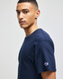 A navy short sleeve t-shirt featuring a logo on the sleeve. The model is facing sideways.