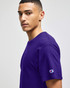 A purple Champion Adult Jersey Short Sleeve T-Shirt worn by a model, featuring a small logo on the sleeve.