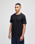 A black short sleeve t-shirt with a logo on the sleeve, displayed by a model standing against a neutral background.