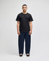 A black short sleeve T-shirt worn with navy blue pants, featuring a logo on the T-shirt.