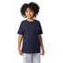 A navy blue youth short sleeve t-shirt, featuring a round neckline and a logo. The model has curly hair and is smiling.