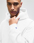 A light grey pullover hooded sweatshirt featuring a logo, worn by a young man with short hair.