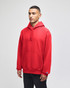 A red pullover hooded sweatshirt with a front pocket and logo on the sleeve, displayed on a model.