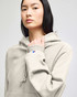 A light grey hooded sweatshirt featuring a kangaroo pocket and a logo on the sleeve.