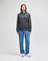 A grey pullover hooded sweatshirt with a front pocket, paired with blue jeans and white sneakers.