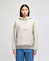 A light grey pullover hooded sweatshirt with a front pocket and a logo on the sleeve, worn by a model.