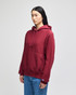 A maroon pullover hooded sweatshirt with a front pocket and a logo on the sleeve. Model wearing denim jeans.