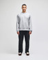 A grey Champion Reverse Weave® adult crew sweatshirt worn by a model, paired with dark trousers and shoes.