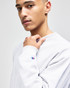 A grey Champion Reverse Weave® adult crew sweatshirt with a logo on the sleeve, modelled by a young man.