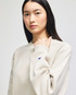A light beige crew sweatshirt with a logo on the sleeve, featured on a model.