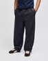 Open-bottom fleece pants in dark grey with pockets, styled with a navy top and brown shoes, featuring a branding logo.