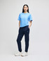 A model wearing navy fleece joggers paired with a light blue t-shirt and white sneakers, featuring a logo.