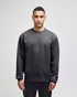 A grey adult crewneck sweatshirt featuring a logo, modelled by a person standing straight.