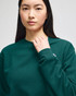 A green crewneck sweatshirt featuring long sleeves and a logo on the sleeve.