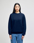 A navy blue crewneck sweatshirt is worn by a model, featuring a small logo on the sleeve.