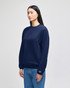 A navy blue crewneck sweatshirt displayed on a model, featuring a small logo on one sleeve.