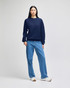 A navy blue crewneck sweatshirt featuring long sleeves and a logo, paired with light blue jeans.